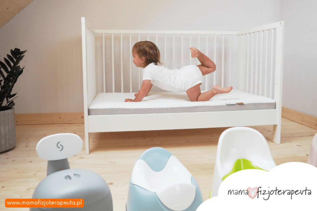 Dziecko leżące na łóżeczku podczas odpieluchowania. Dzienne odpieluchowanie dziecka. Jak i kiedy odpieluchować dziecko. Odpieluchowanie 2 latka. Mama Fizjoterapeuta